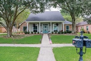 A front view of an Acadian renovated home with columns, sidewalks and a colorful front door recently purchased with the changing real estate market