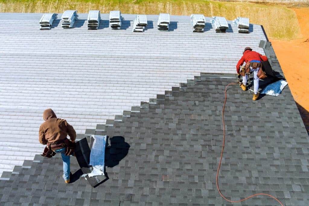 worker installing bitumen roof shingles