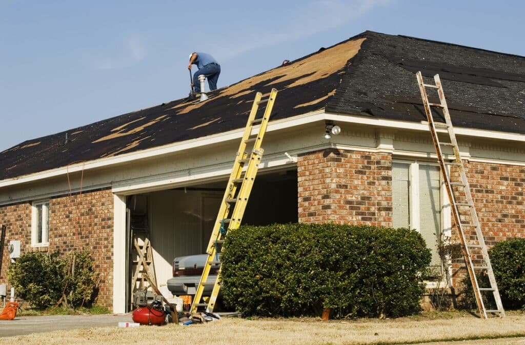 worker repairing shingles